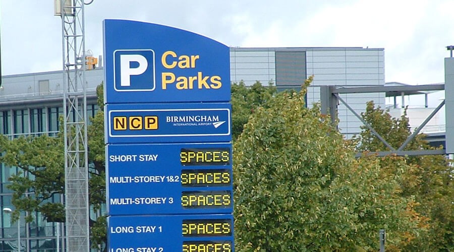 Illuminated car park entrance sign with automated space count display, showing live availability across multiple parking zones.