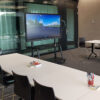 75 inch 4K interactive touch display mounted on a mobile trolley stand in a glass-walled meeting room with conference table and seating.