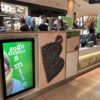43 inch digital display built into a smoothie bar counter, showing "so go on and smile" health messaging.