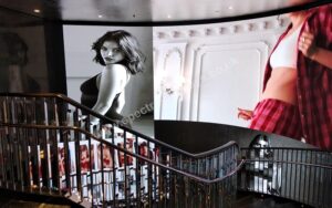 Curved LED display installed above a spiral staircase, showing large-scale fashion imagery that follows the sweeping architectural line of the stairwell.