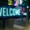 Illuminated LED sign displaying "WELCOME" at a hotel entrance at night, with ambient lighting visible in the background.