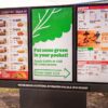 Outdoor digital menu board with three screens displaying a fast-food restaurant's meal, sides, and dessert menu.