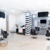 Modern hair salon interior featuring a wall-mounted digital display above the styling stations.