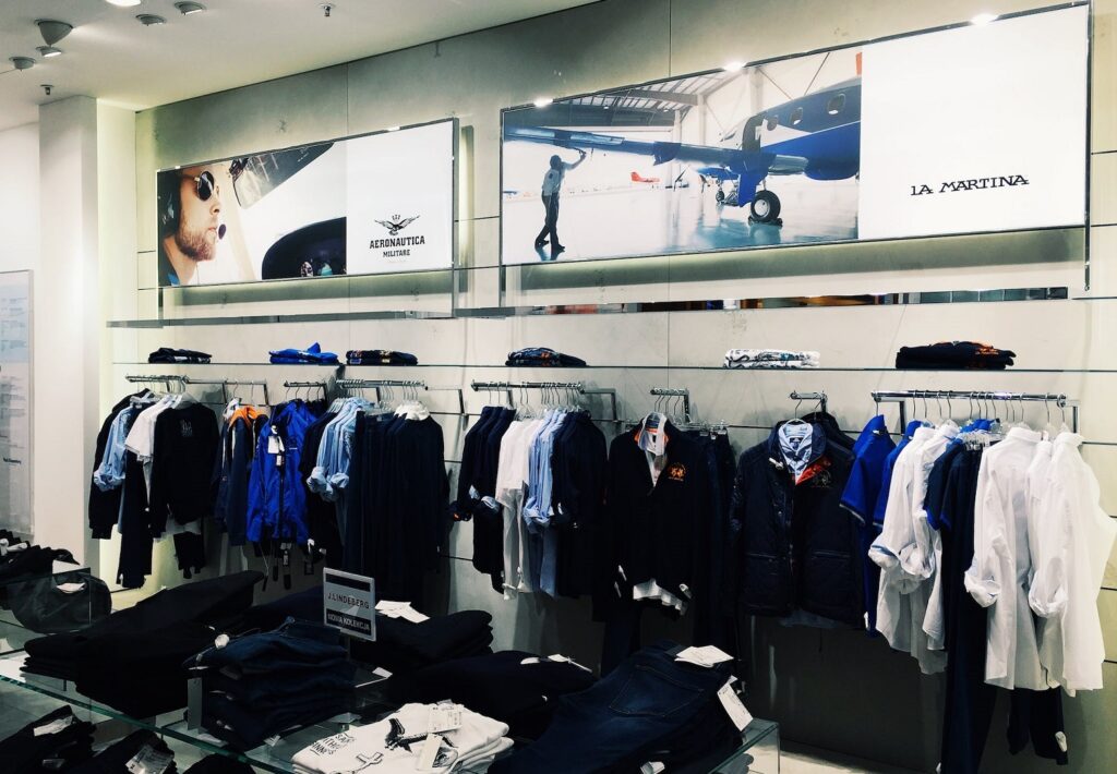 Retail clothing store interior with garment displays and branded lifestyle imagery.