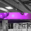 Circular halo-shaped flexible LED display suspended from the ceiling above a retail floor, showing vivid pink and purple graphic content.