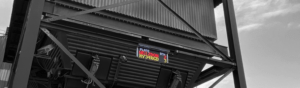 LED text display mounted beneath an industrial hopper, showing vehicle plate and weight information for site logistics.