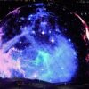 Completed spherical venue exterior at night, displaying a full-motion colourful LED light show visible across its entire curved surface.