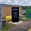 Outdoor digital signage totem installed at a recycling centre entrance, positioned near the site office and weighbridge.
