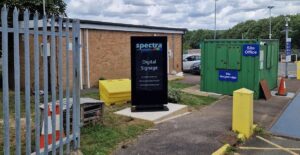 Outdoor digital signage totem installed at a recycling centre entrance, positioned near the site office and weighbridge.