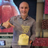 Image shows Mike Boxall, Managing Director of Spectra Displays Limited holding a celebration cake in front of a dvLED display.