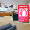 Freestanding DV-LED totem display on castors, showing a promotional offer in a furniture showroom.